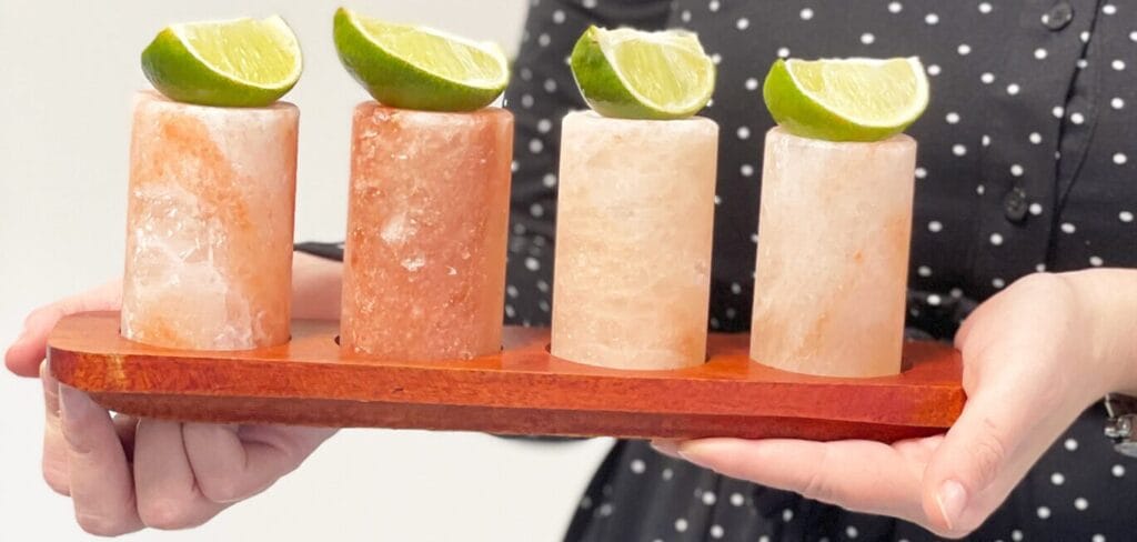 four Himalayan crystal rock salt shot glasses on a wooden serving tray