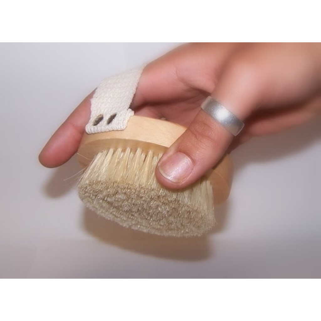 a hand held body scrub brush being held in a hand