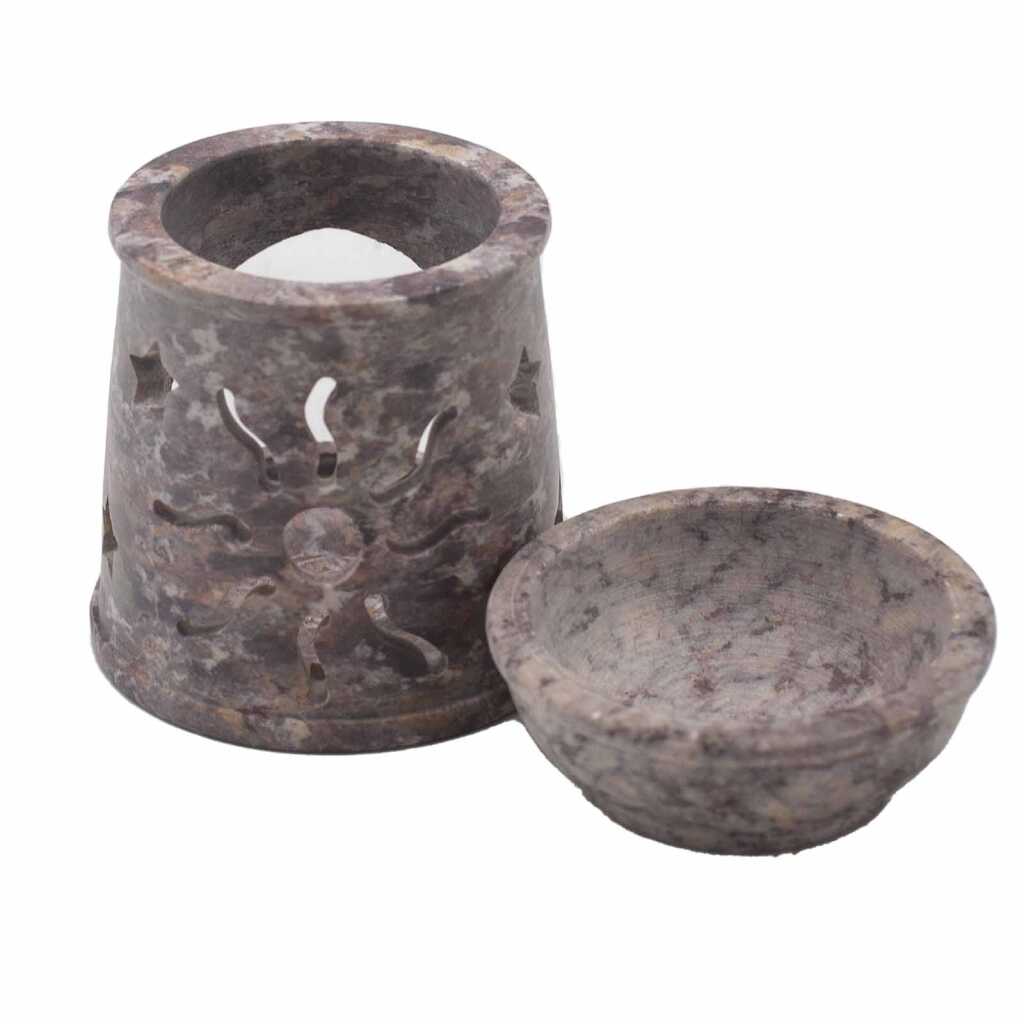 a soapstone oil burner with a sun and stars design, showing the base and the bowl separately.