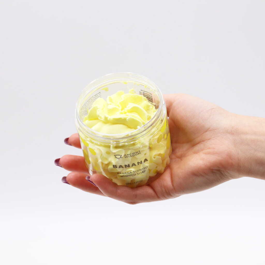 banana scented whipped soap - yellow - open jar in an open hand
