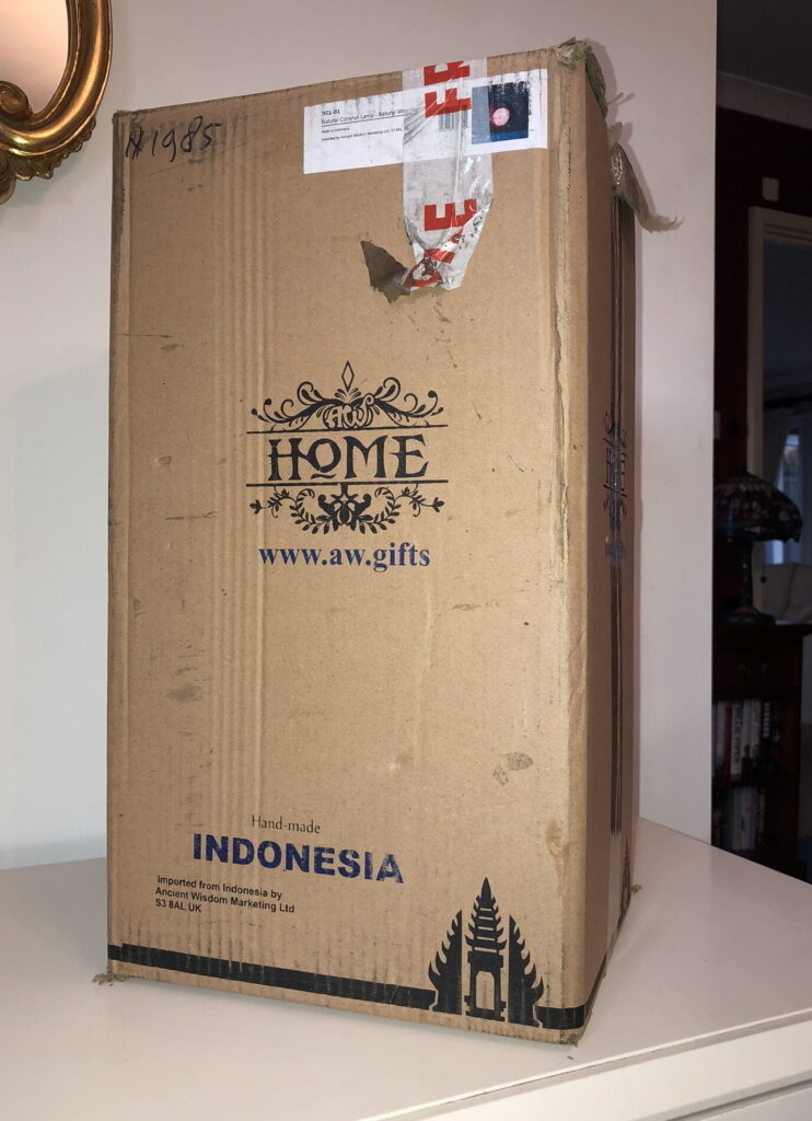 a brown, closed box, containing a coconut leaf lamp