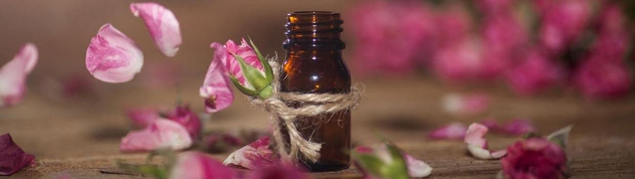 an empty aromatherapy bottle on a table surrounded by pink petals and flower buds