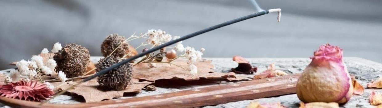 an incense stick burning almost horizontally in a wooden holder