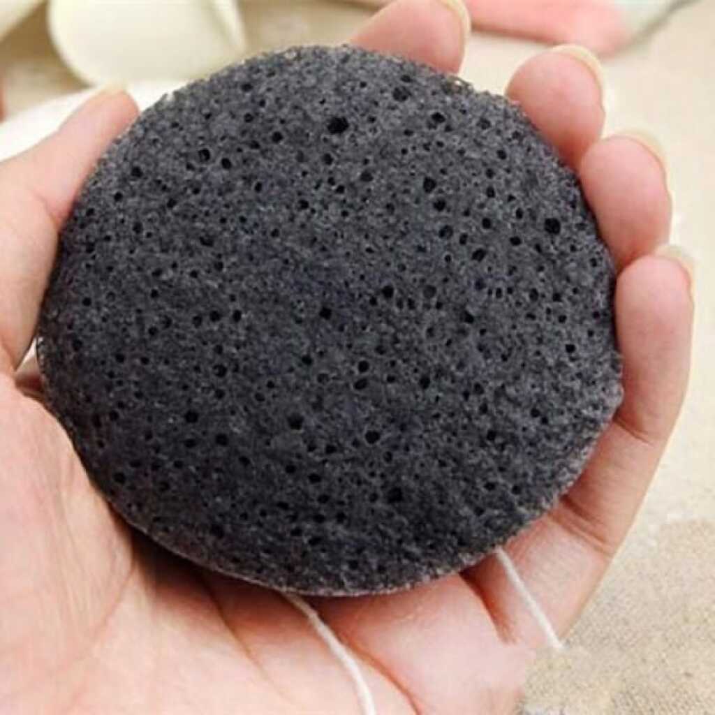 a charcoal coloured konjac sponge in a hand