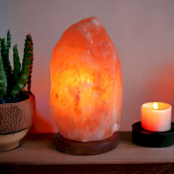rock salt lamp on a table wit candle and plant
