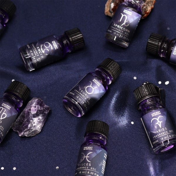 a selection of zodiac fragrance oils on a bleu satin cloth