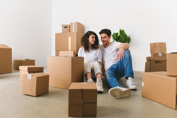 two people sitting on the floor surrounded by boxes