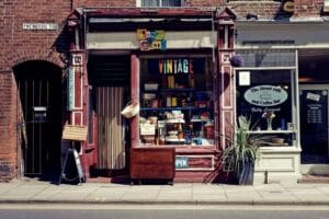 a vintage store stocking everything and a coffee shop next to each other on a road.