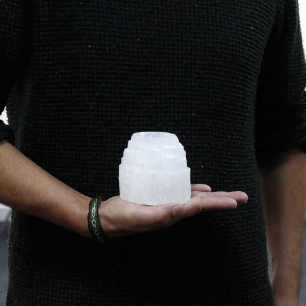a selenite mountain top design candle holder for tealights resting in the palm of a hand