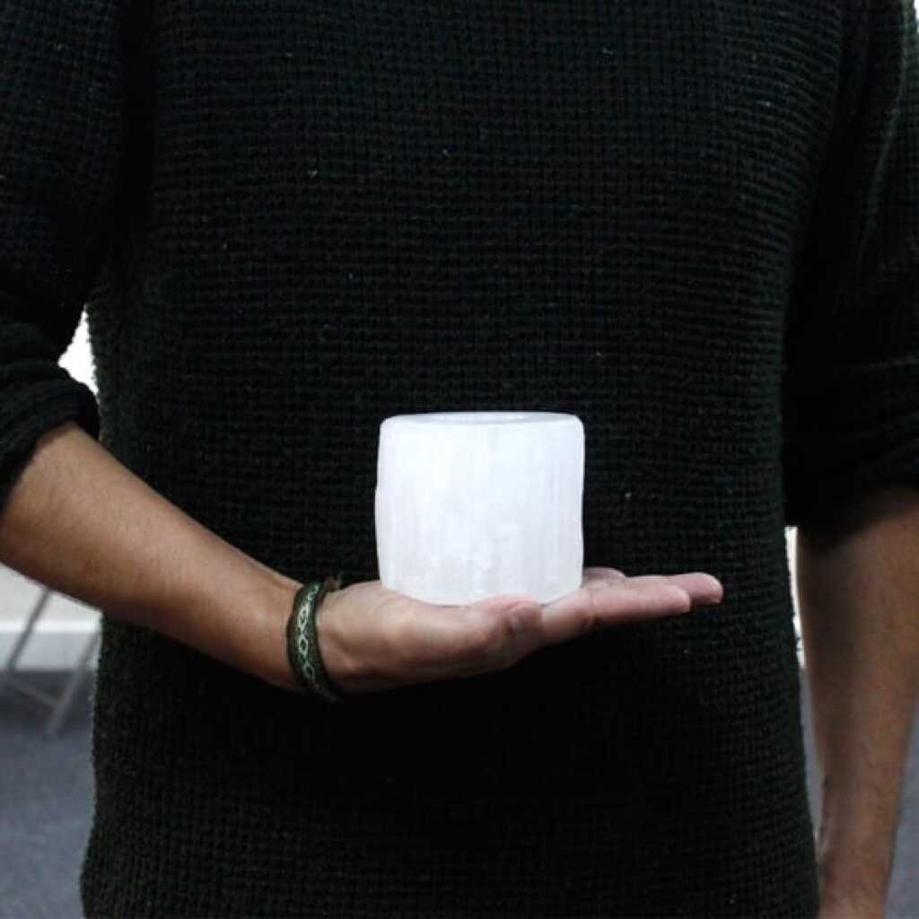 a selenite cylinder design candle holder for tealights resting in the palm of a hand