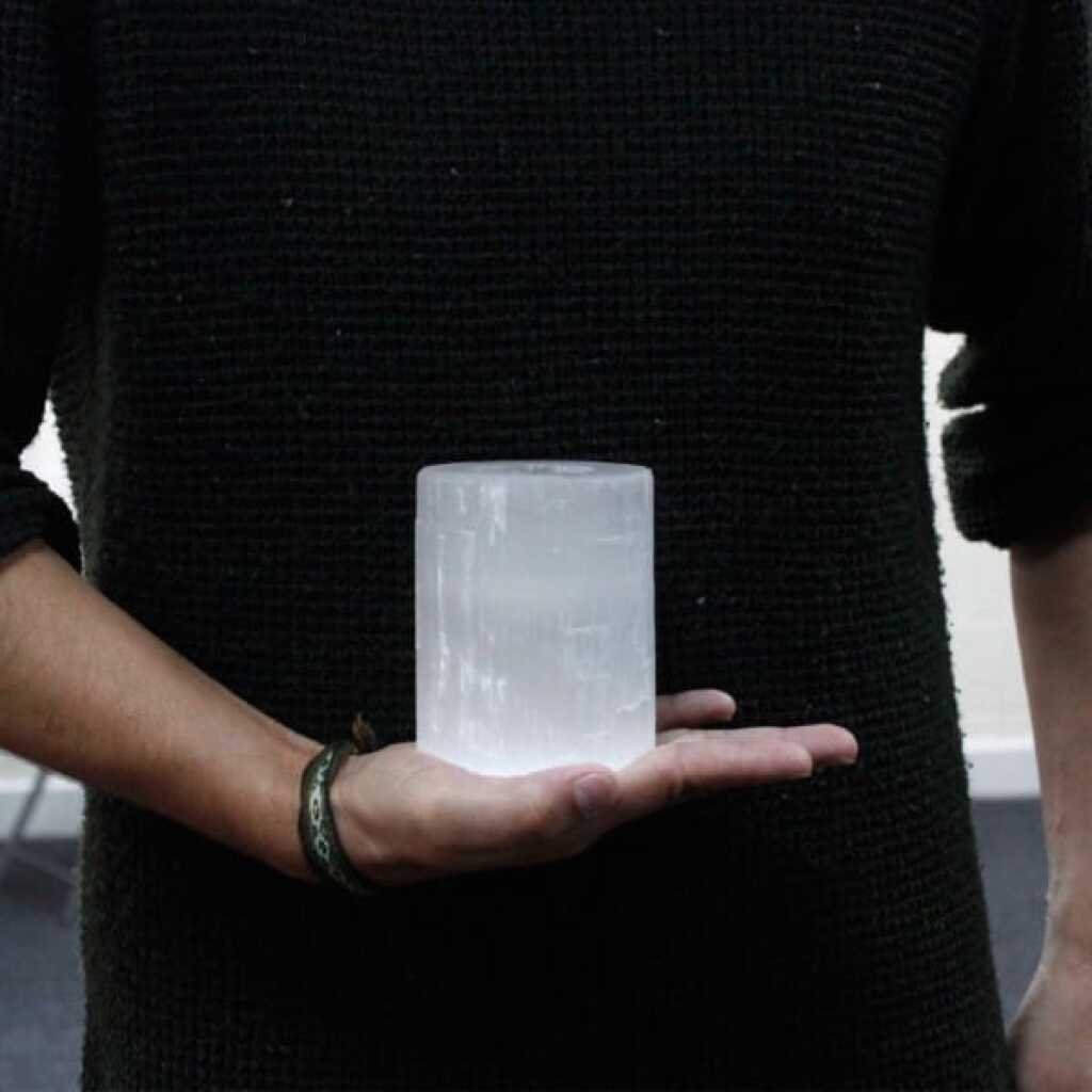 a selenite cylinder design candle holder for tealights resting in the palm of a hand