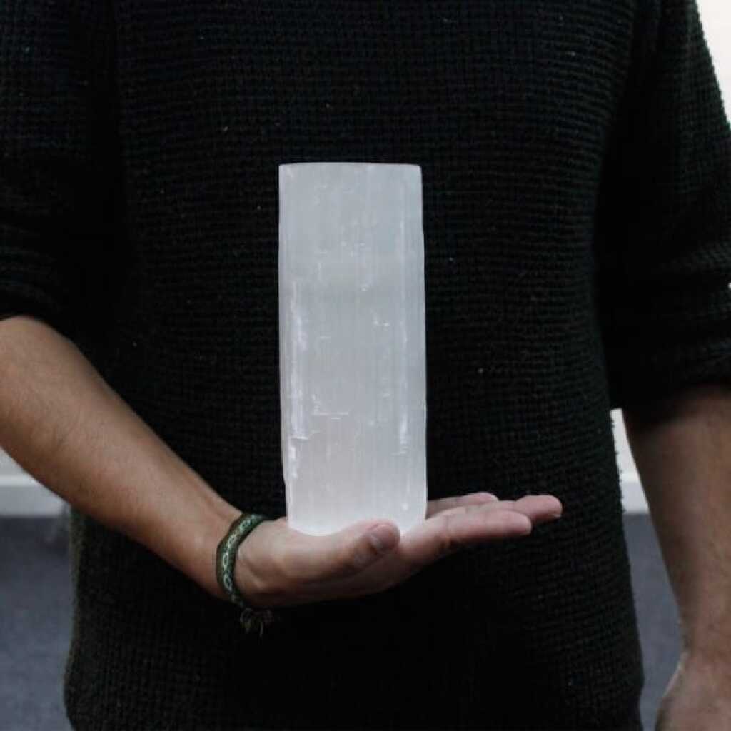 a selenite cylinder design candle holder for tealights resting in the palm of a hand