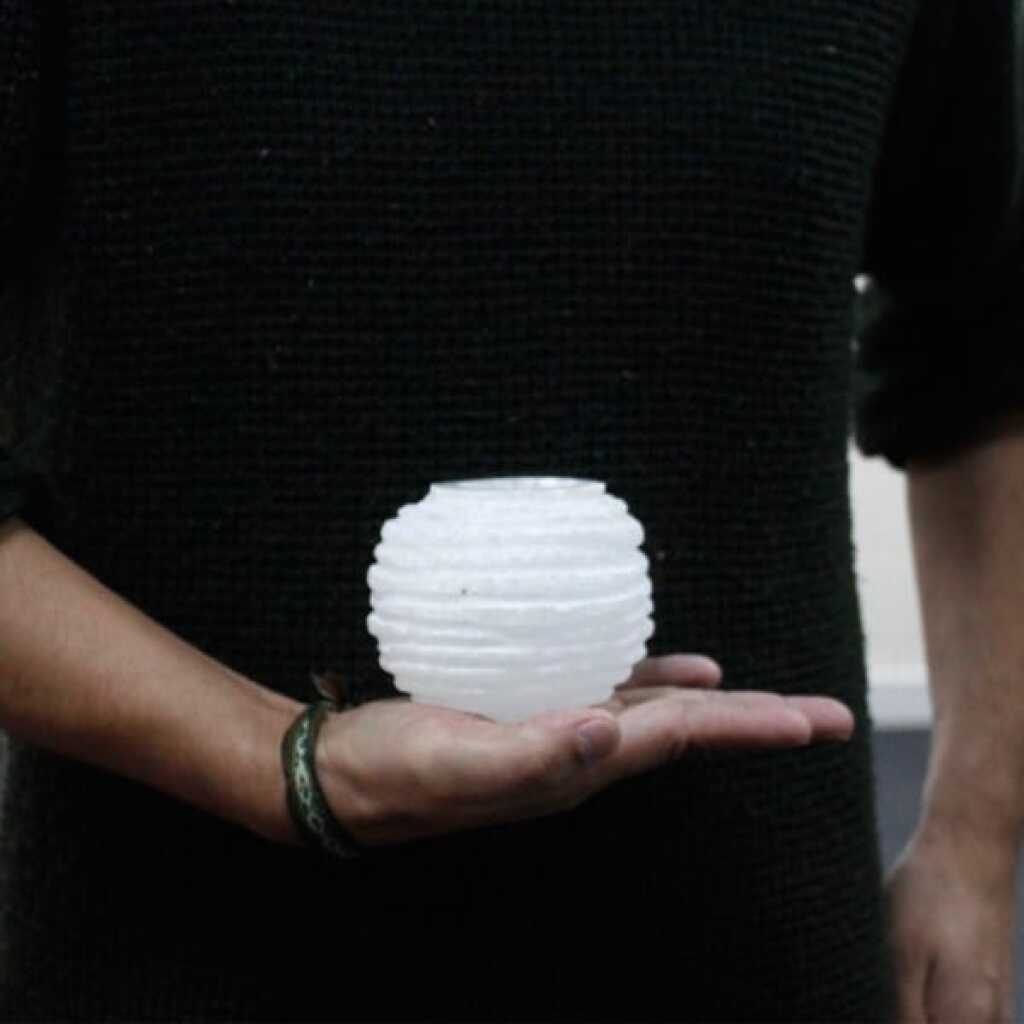 a selenite snowball design candle holder for tealights resting in the palm of a hand