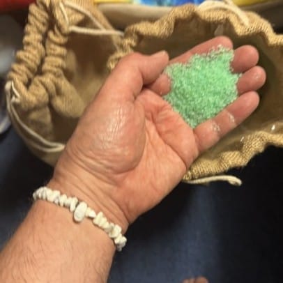 green bath potion n an open hand with a white jasper chipstone bracelet on the wrist