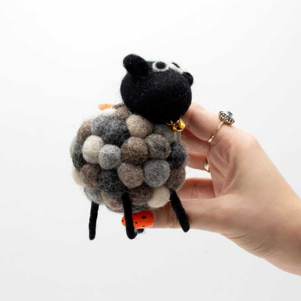 a little felt sheeps in various shades of grey with a black head held in a hand