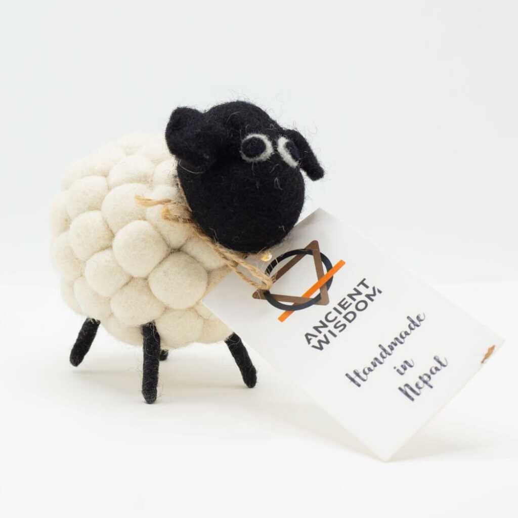 a little felt sheeps in white with a black head with a label around its neck