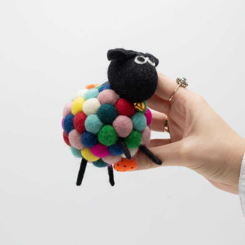 a little felt sheeps in multi-colours with a black head held in a hand