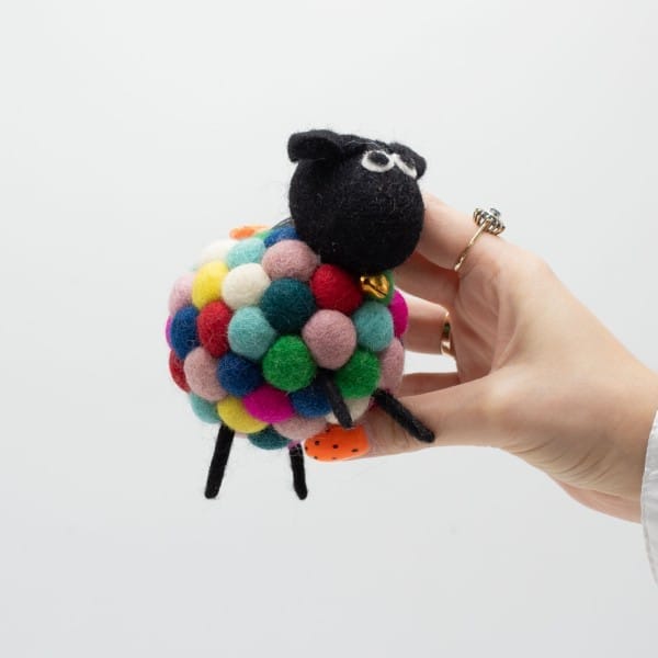 a multicoloured felt sheep held in a hand