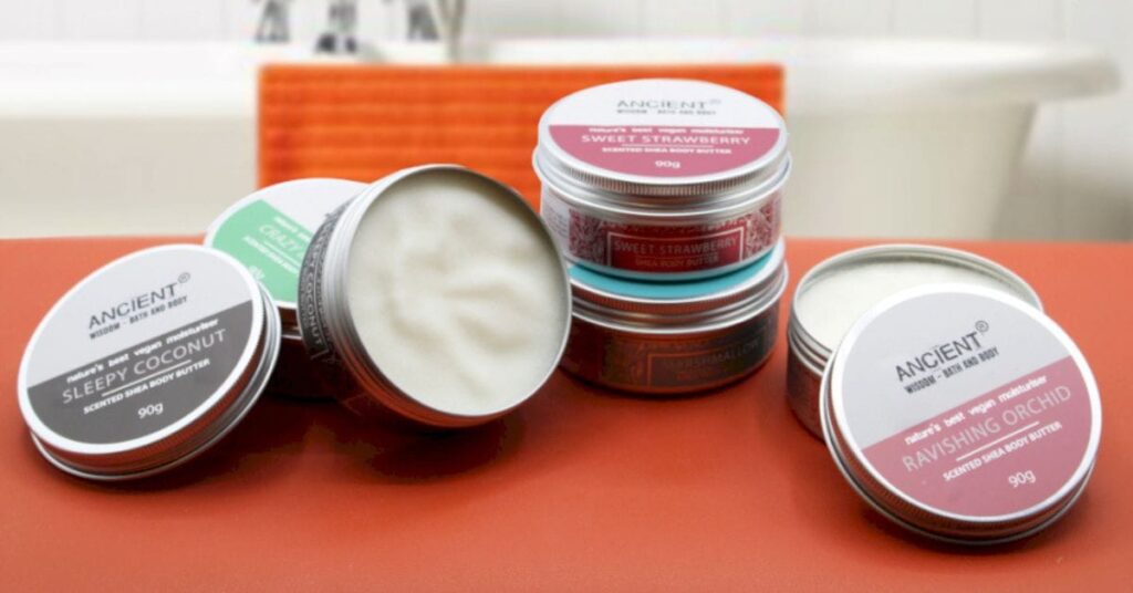 several tins of scented shea body butters on an orange table top