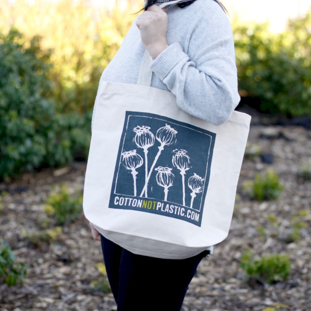 a white "say no to plastic" eco-cotton bag being carried over the shoulder