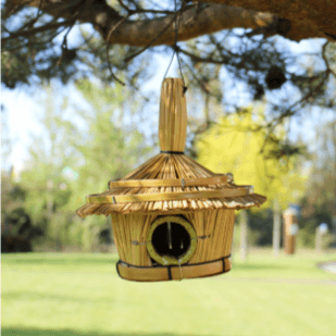 A seagrass birdhouse hanging from a tree branch