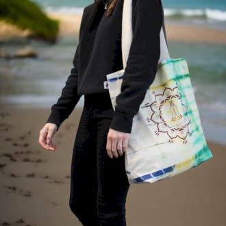 a tie dye cotton bag being carried on a beach